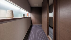 Un couloir étroit avec un sol à rayures, un vase posé sur une étagère et des murs en bois.