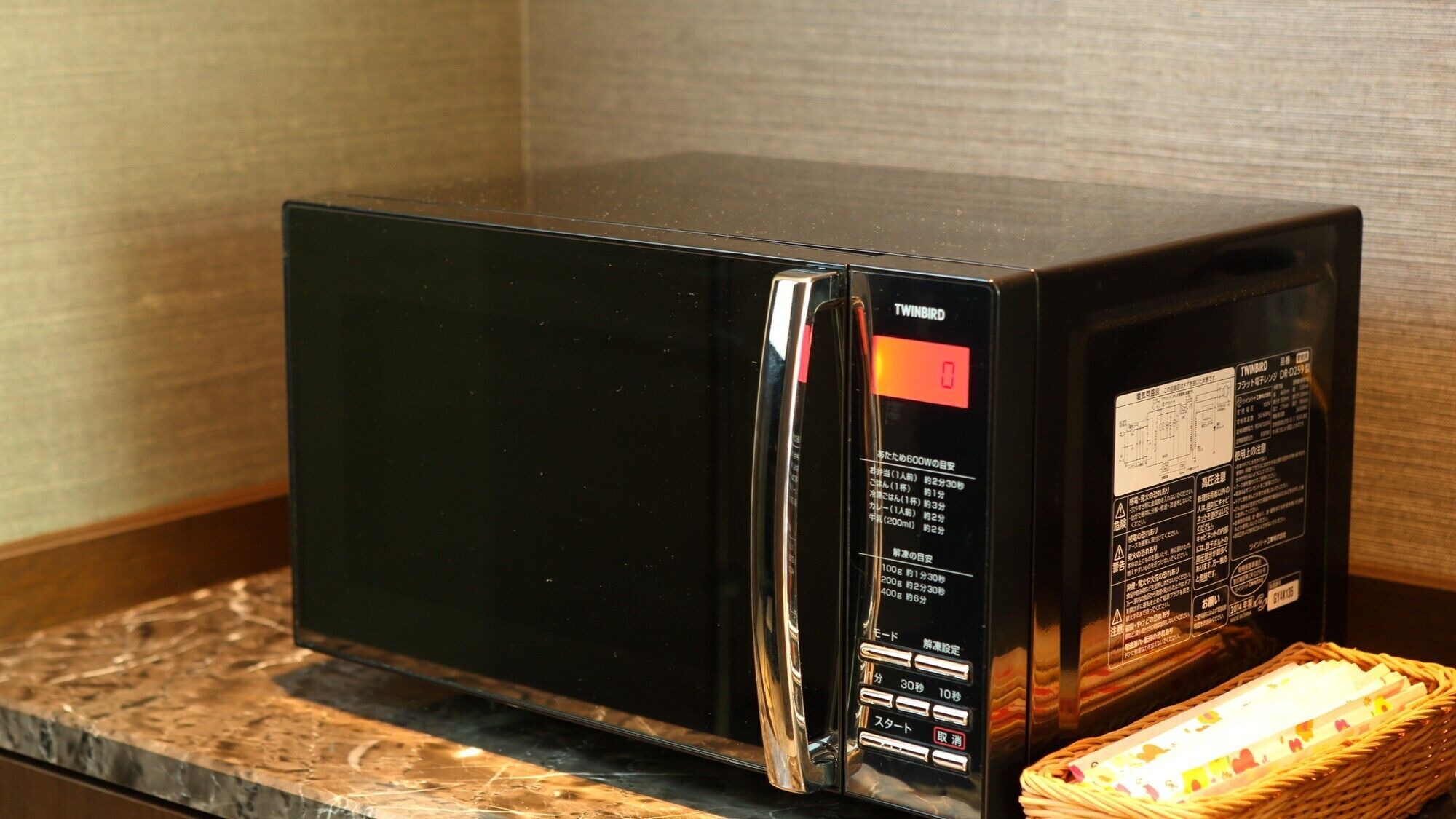 Un four à micro-ondes noir, doté d’un panneau de commande situé sur le côté droit, posé sur une surface en bois.