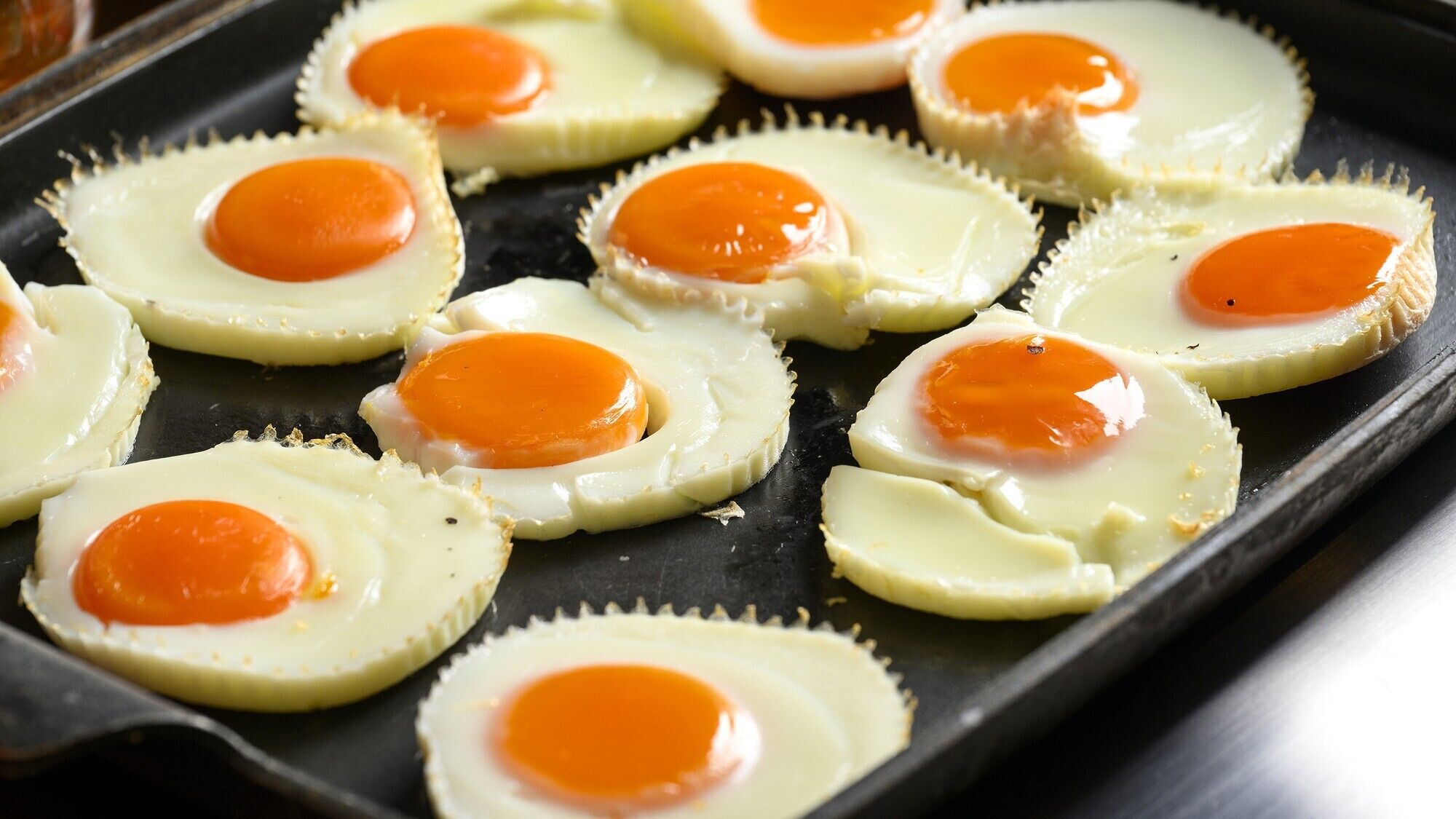 A tray of fried eggs on a black surface.