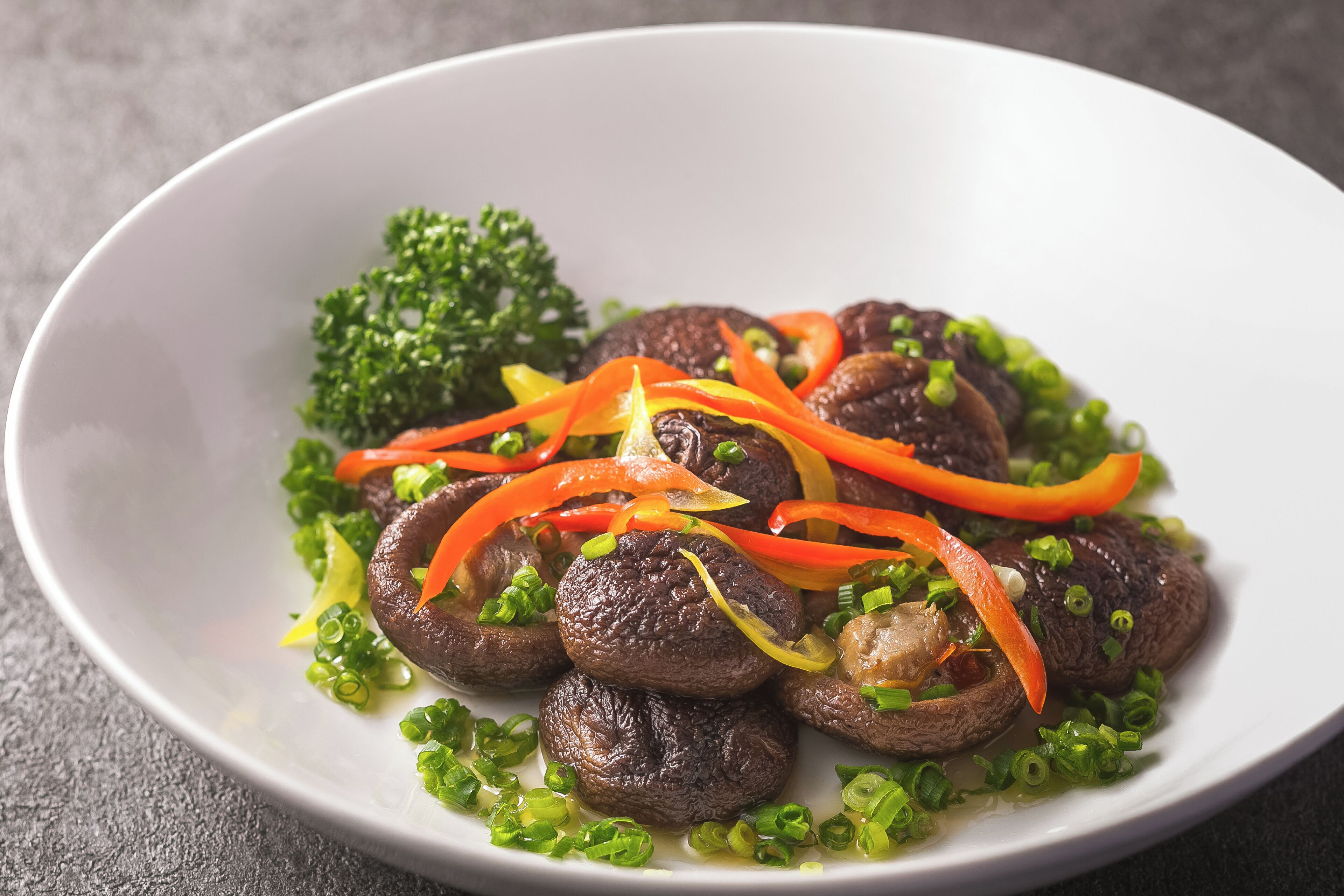 A white plate with sliced mushrooms, carrots, and green onions.