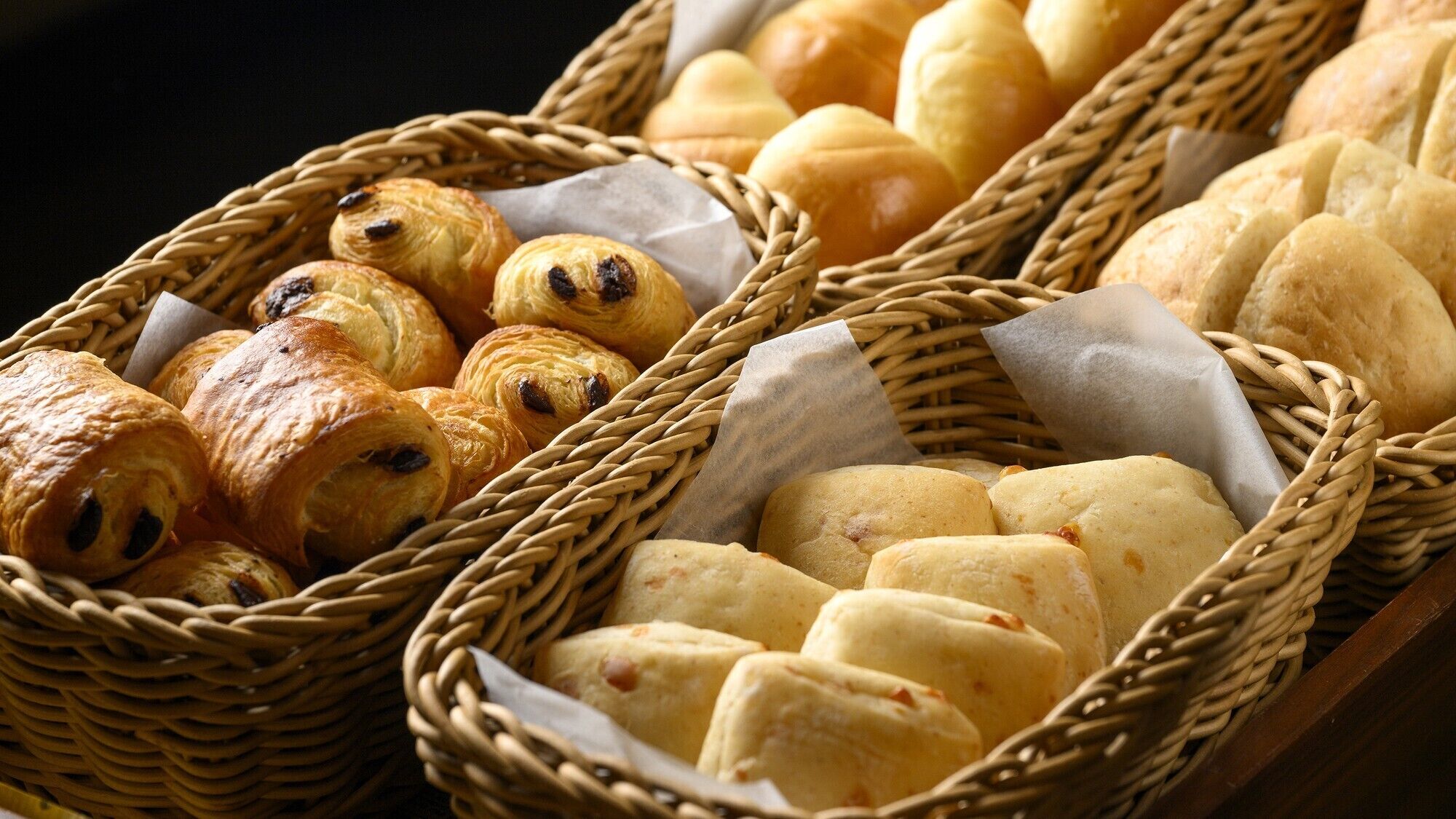 Three wicker baskets filled with various baked goods.