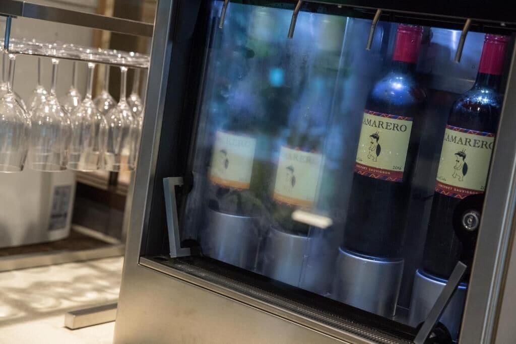 Um refrigerador de vinhos com garrafas rotuladas 'MARERO' e um suporte para copos de vinho.