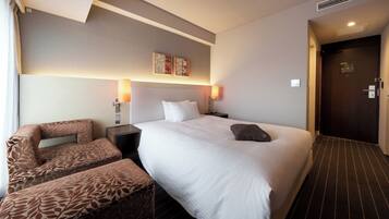 A hotel room with a large bed, two bedside tables, a chair, and a door.
