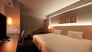 Une chambre d’hôtel avec un grand lit, un bureau avec un téléphone et une chaise.