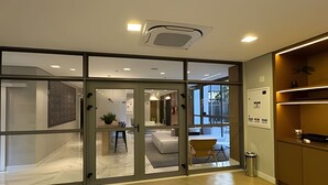 Un interior moderno con puertas de vidrio que dan a un comedor, una planta pequeña y un cubo de basura.