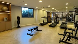 Un gimnasio con cintas de correr, bancos y máquinas de pesas.