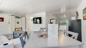Una habitación moderna con una mesa de comedor, sillas, un televisor y un cartel de bienvenida.