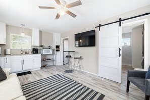 Eine moderne Küche mit weißen Schränken, einer schwarzen Arbeitsplatte und einem Deckenventilator.