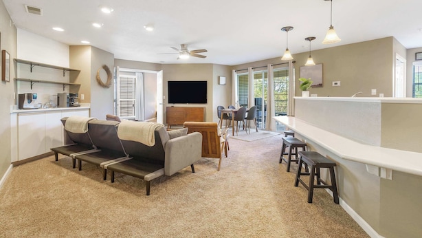 A spacious living area with a sofa, a coffee table, a TV, and a dining area with chairs.