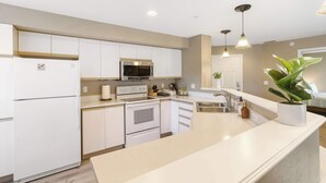 A modern kitchen with white cabinetry, a built-in oven, a microwave, and a sink.