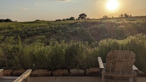Ein hölzerner Stuhl und eine Bank in einer natürlichen Umgebung mit Blick auf einen grasbewachsenen Feld bei Sonnenuntergang.