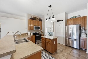 A modern kitchen with wooden cabinets, stainless steel appliances, and a central island. - Pool Retreat Near Mayo & Beaches (Jacksonville)