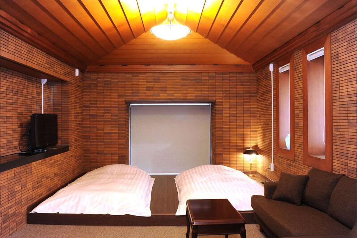 Una habitación con dos camas, un sofá, un televisor y una lámpara en el techo.