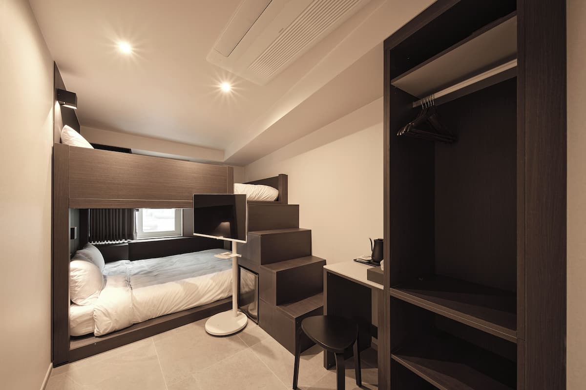 Une chambre moderne avec un lit superposé, un bureau et un dressing.