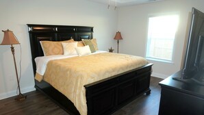 A bedroom with a dark wood bed, a large window, and a TV stand. - Masters Week Rental • 11 Miles to Augusta National • Masters Week Ready (Augusta)