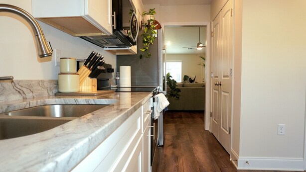 A kitchen with a double sink, white cabinets, and a wooden floor. - Masters Week Rental • 11 Miles to Augusta National • Masters Week Ready (Augusta)