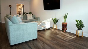 A living room with a sofa, a flat-screen TV, and potted plants. - Masters Week Rental • 11 Miles to Augusta National • Masters Week Ready (Augusta)