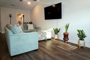 Una sala de estar con un sofá, un televisor de pantalla plana y plantas en macetas.