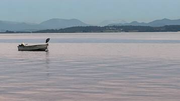 A small boat on calm water with a mountain range in the background.