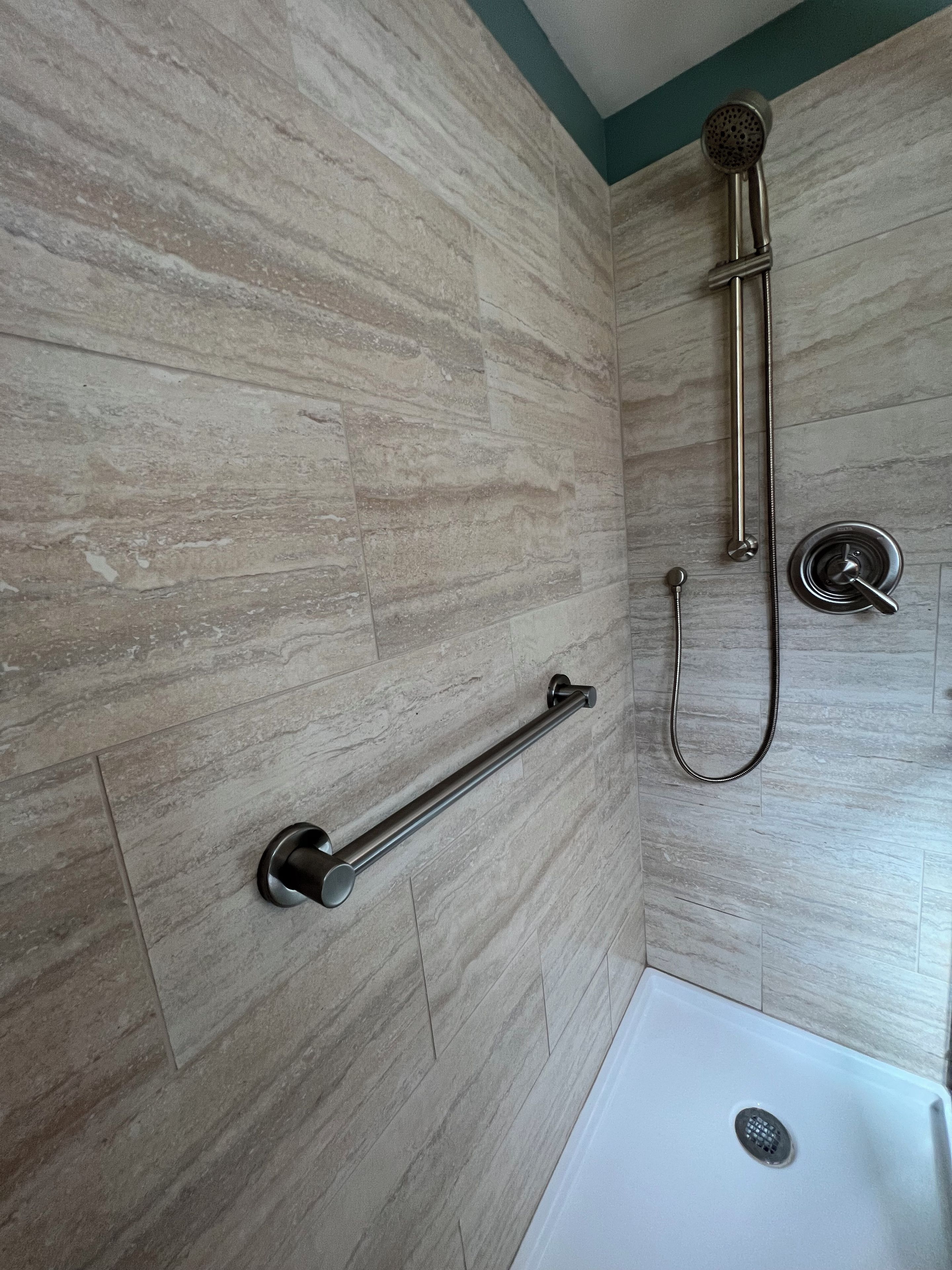 A bathroom with a shower, a grab bar, and a bathtub.
