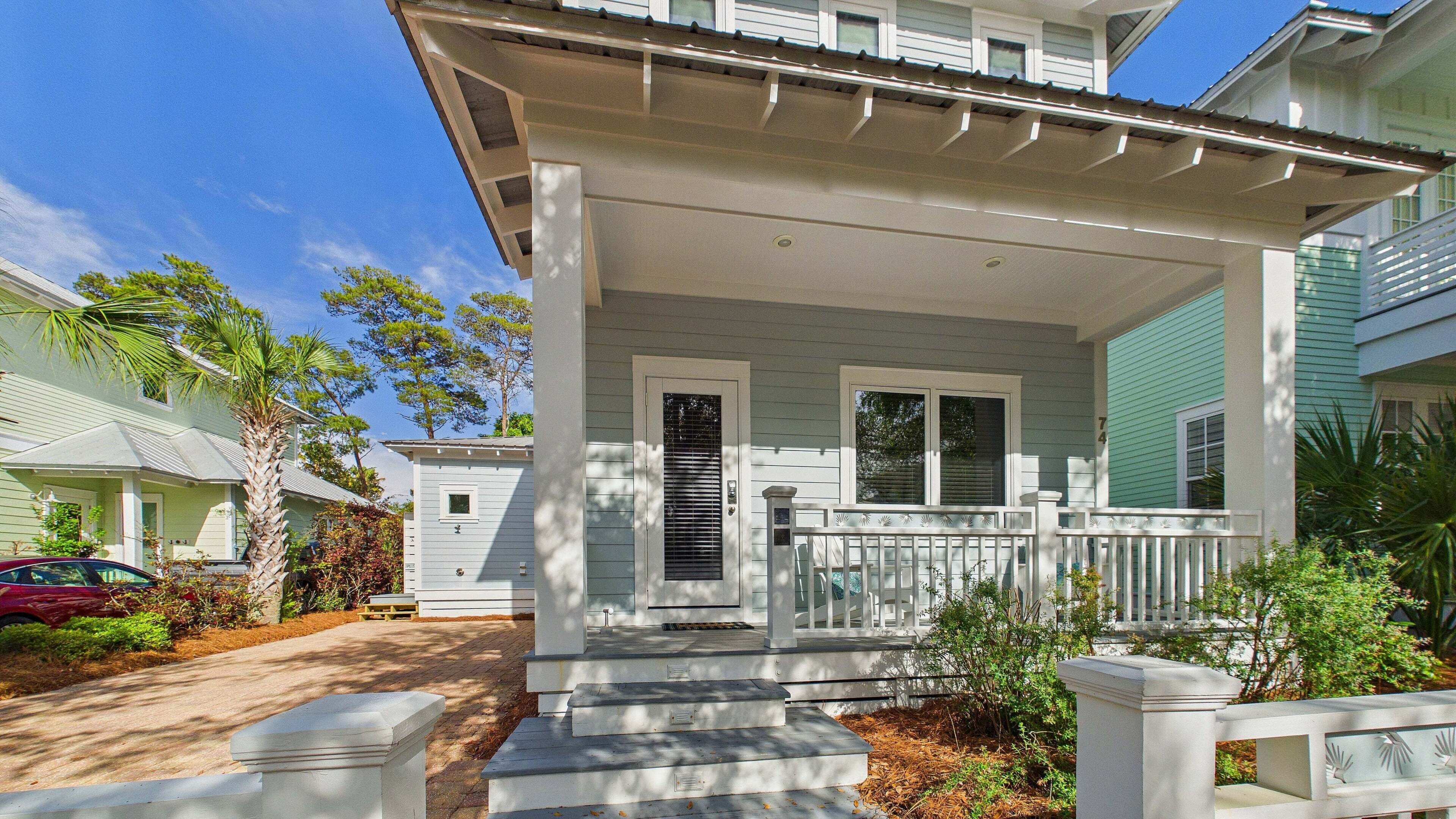 A two-story house with a front porch, a driveway, and a palm tree.