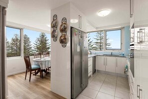 Una cocina moderna con comedor, ventanas amplias y vistas a árboles.