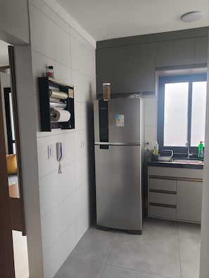 Uma cozinha moderna com geladeira de aço inoxidável, forno embutido e janela sobre a pia.