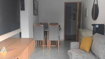 Un soggiorno moderno con un tavolino in legno, un divano grigio e un'area pranzo con sedie.