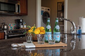 Una encimera de cocina con una botella de agua Pellegrino, un vaso y limones.