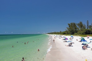 A beach with clear turquoise water, people swimming and sunbathing, and beach umbrellas. - Bayshore Bungalow- Located near Beaches & Downtown (Naples)
