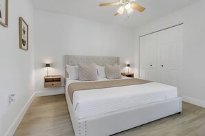 Ein Schlafzimmer mit einem Bett, Nachttischen, einem Deckenventilator und einem Kleiderschrank.