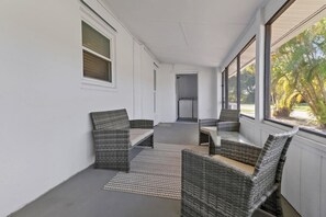 A covered patio area with wicker furniture and a view of the outdoors. - Bayshore Bungalow- Located near Beaches & Downtown (Naples)