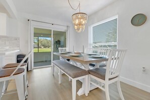 Ein Essbereich mit einem Tisch für vier Personen, weißen Stühlen und einer Chandelier.