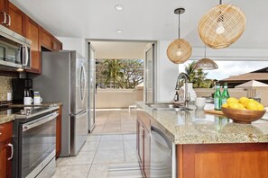 Eine moderne Küche mit Edelstahlgeräten, einer Arbeitsplatte aus Granit und Blick ins Freie.