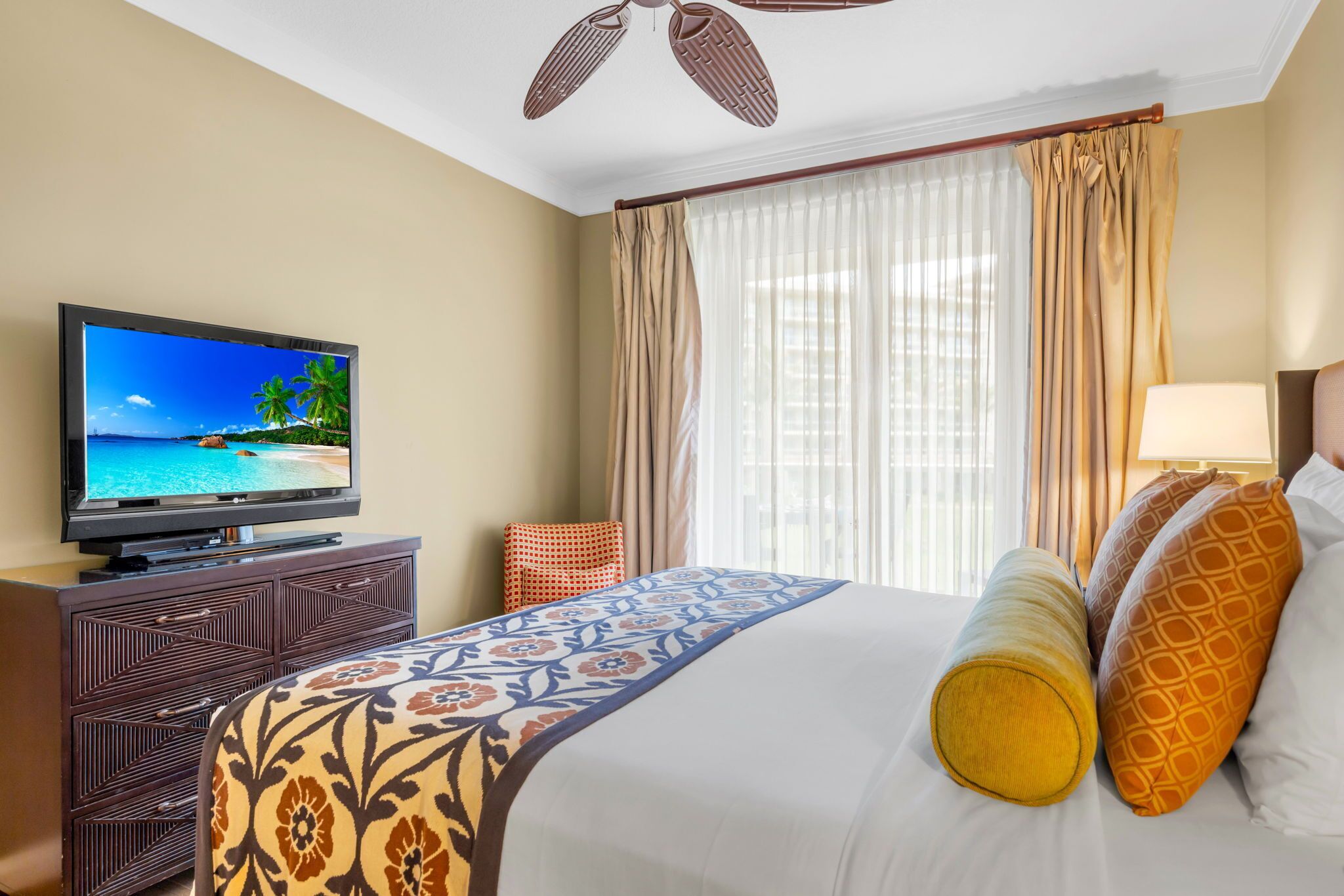 Une chambre d’hôtel avec un lit, une télévision, un bureau et une fenêtre avec des rideaux.