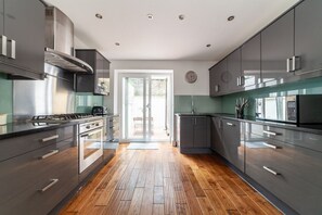 A modern kitchen with stainless steel appliances, wooden flooring, and a view to the outside. - Boutique London Townhouse | Sleeps 10 | (London)