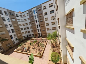 A multi-story residential building with balconies, a courtyard with plants, and a tiled walkway. - Bright & Cozy Apartment 10 min Beach agadir (Agadir)