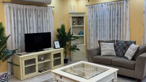 A living room with a television, sofa, and a coffee table. - Spacious 5-bedroom villa in beautiful Lowlands with AC (Lowlands)