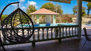 A covered outdoor area with a pool, lounge chairs, and a gazebo. - Spacious 5-bedroom villa in beautiful Lowlands with AC (Lowlands)