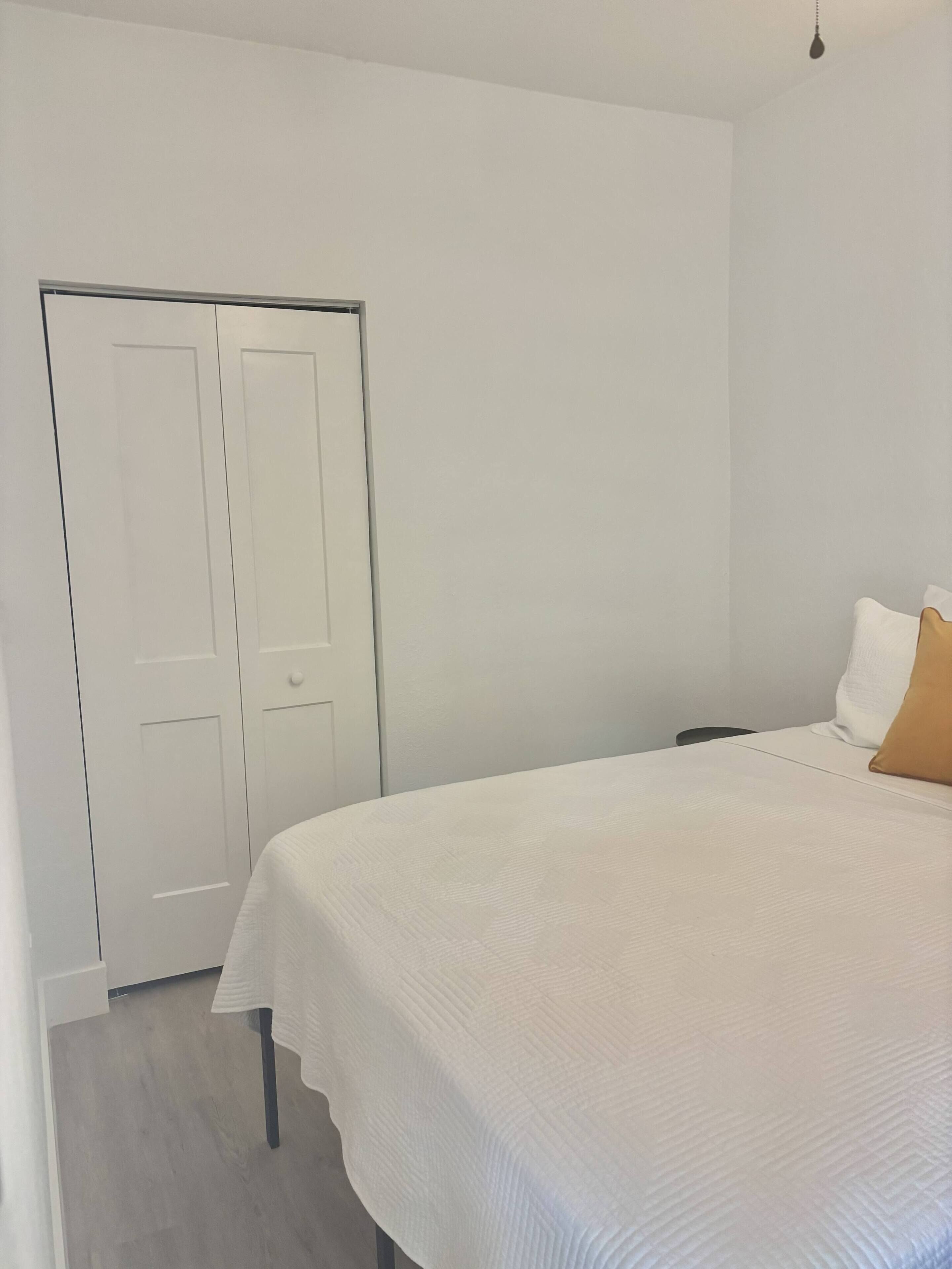 A bedroom with a bed, a wardrobe, and a nightstand.