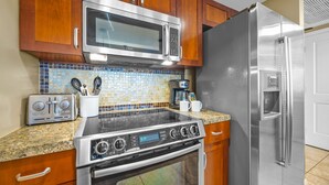 Una cocina con electrodomésticos de acero inoxidable, armarios de madera, salpicadero de azulejos y encimera de granito.