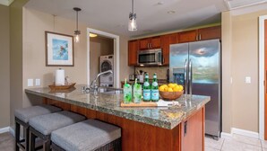 Una cocina con una isla de granito, electrodomésticos de acero inoxidable y un ventanal grande.