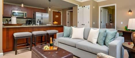 A modern kitchen with a microwave, refrigerator, and bar stools.