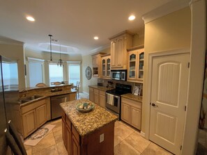 A kitchen with granite countertops, stainless steel appliances, wooden cabinets, and a white door. - R Three by the Sea/Coastal Retreat in Laguna Vista (Laguna Vista)