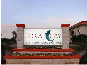 Schild für die Strandwohnungen Coral Cay mit einem Delphin-Logo.