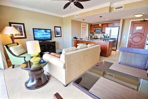 A living room with a sofa, TV, and a dining area with a table and chairs. - Honua Kai | Ocean View 2 BR, Sleeps 8 | Car Incl. w/ 6+ Nights | HKH ML-2870 by KBM (Lahaina)