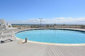 Ein Pool mit Holzterrasse, Metallgeländer und freiem Blick auf den Ozean.