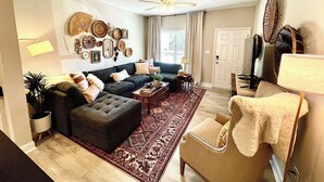 A living room with a sofa, ottoman, coffee table, and a patterned rug. - Sparkle City Vibes await for you to relax and enjoy! (Spartanburg)