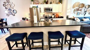 A kitchen with a central island, bar stools, a microwave, and cabinets. - Sparkle City Vibes await for you to relax and enjoy! (Spartanburg)