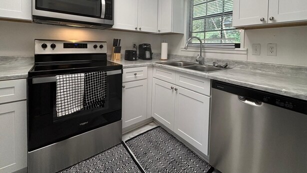 A modern kitchen with white cabinets, a stainless steel dishwasher, a microwave, and a stove. - Close to Hospitals, Masters & Downtown (Augusta)